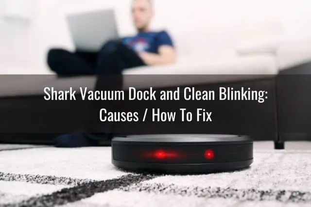 Robotic vacuum with blinking red lights on a rug