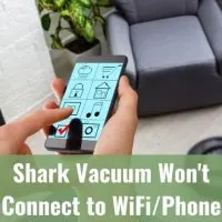 A person using a smartphone app to control robotic vacuum