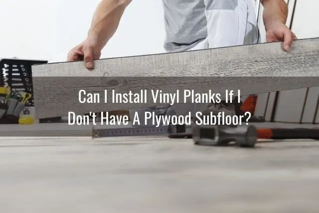 Man lifting and placing a gray vinyl floor plank onto floor
