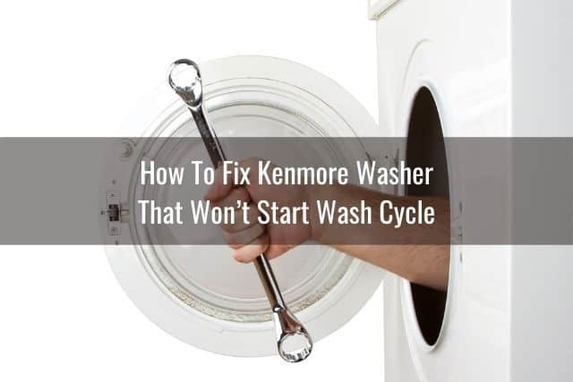 Washing machine door open with a hand holding a wrench