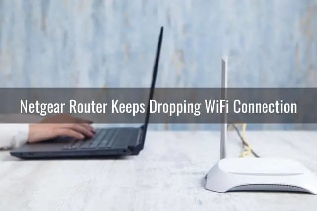 A black laptop and white wireless router with their backs to each other