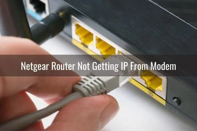 A hand plugging an Ethernet cable into a cable modem port