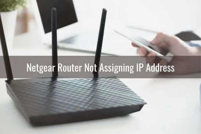 Black wireless router with a phone in the background