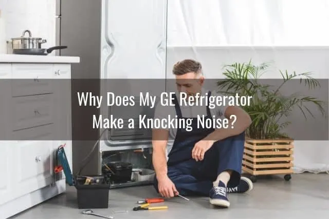 Repairman sitting on ground next to refrigerator