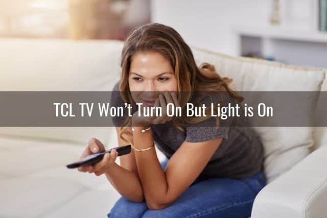 Woman holding a TV remote and sitting on white sofa