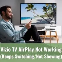 Male using phone while TV is on in the background