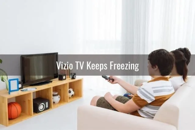 Two people sitting on sofa turning TV on