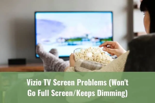 Person sitting on sofa with legs up on table eating popcorn and watching movie