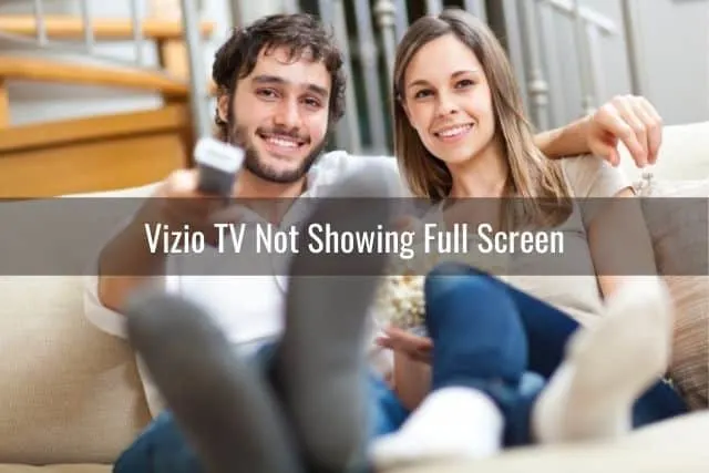 White couple smiling and watching TV together