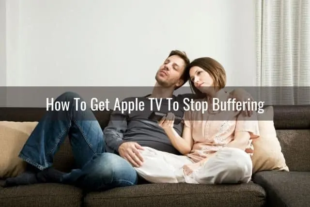 Bored couple sitting on sofa watching TV
