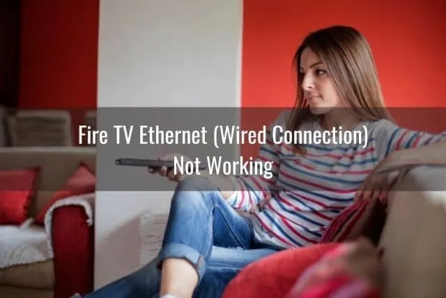 Female sitting on sofa with legs crossed and watching TV