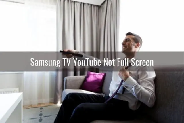 Male sitting on sofa using TV remote to change channels