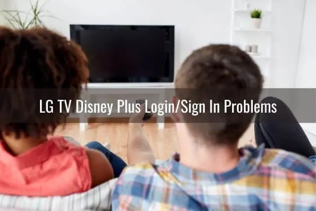 Couple sitting on sofa about to turn on TV with remote