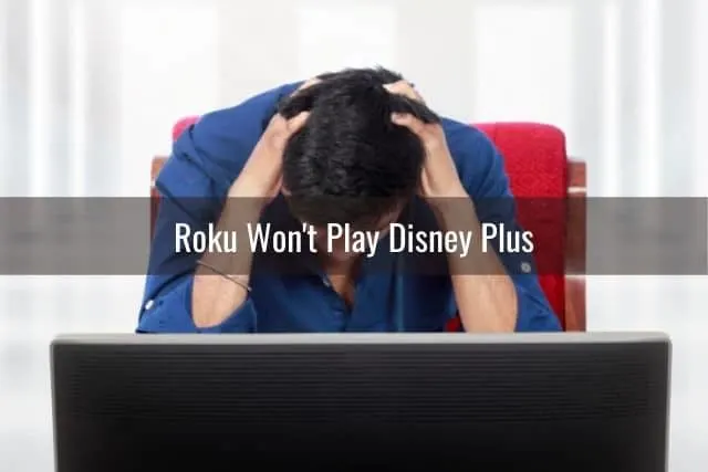 Frustrated male sitting in front of TV with hands over head
