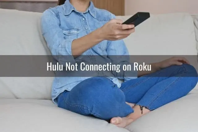 Female sitting on sofa using TV remote
