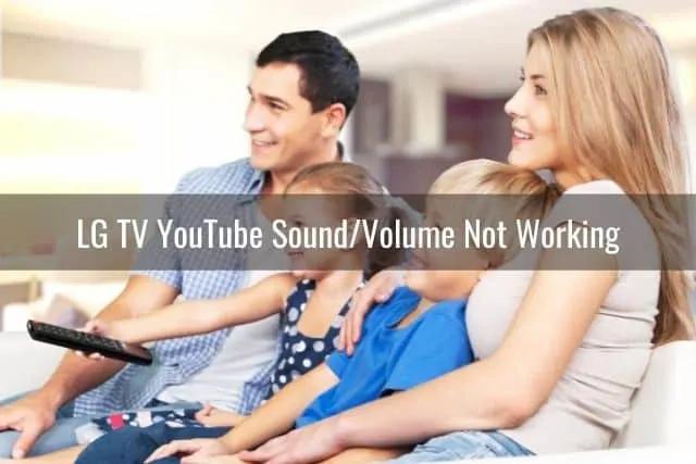 Family of four sitting on living room sofa watching TV