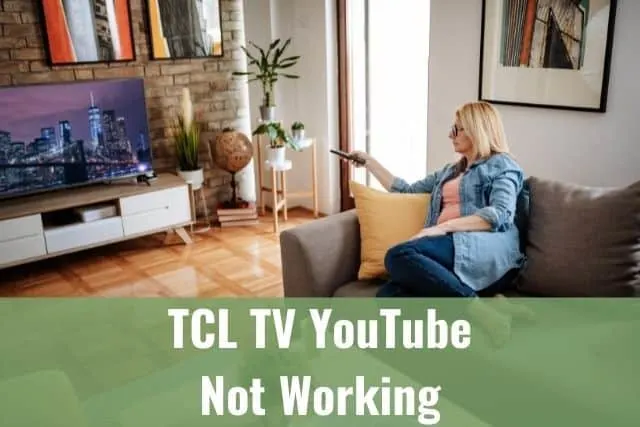 Female senior sitting on couch using TV remote to change channels