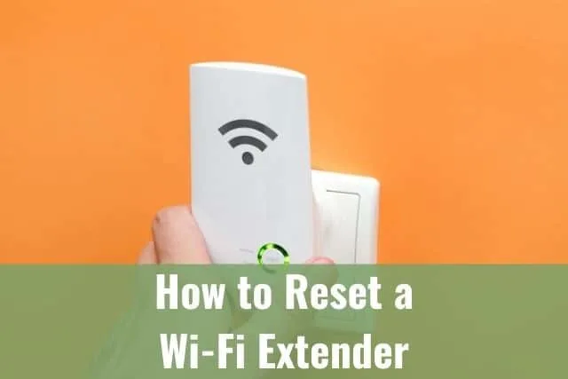 Hand plugging in WiFi Extender into wall socket