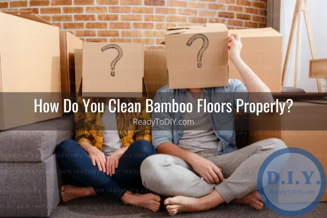 Couple sitting on ground with carboard boxes over head